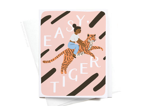Illustration of a woman with a bun riding a tiger on a pink, black-striped background. The Easy, Tiger Greeting Card – FINAL STOCK by Onderkast Studio features bold white letters and premium quality—perfect for any occasion.