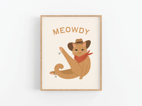The Meowdy Cat Art Print by Onderkast Studio features a brown cat in a cowboy hat and red bandana, raising a paw beneath the word MEOWDY. Framed and set against a white background, it’s an ideal piece for cat lovers.