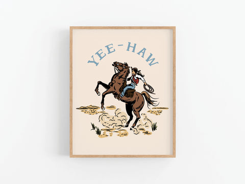 The Yeehaw Cowgirl Art Print by Onderkast Studio features a framed illustration of a cowboy on a rearing horse with YEE-HAW in blue above, set against a minimal background for true country flair.
