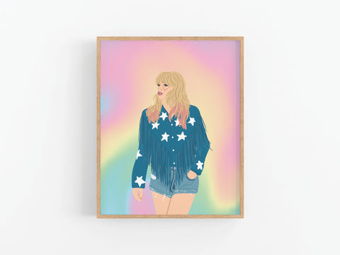 The TS Lover Art Print by Onderkast Studio showcases a blonde woman in a blue star-patterned fringed jacket and denim shorts, set against a pastel rainbow gradient, with vibrant colors displayed on a white wall.
