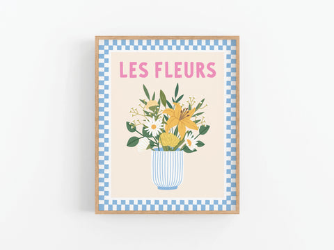 The Les Fleurs Art Print from Onderkast Studio features an illustrated vase of mixed flowers and green leaves, a blue checkered border, and “LES FLEURS” in pink text on a light background for a touch of Parisian elegance.