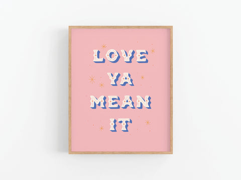 The Love Ya Mean It Art Print by Onderkast Studio features bold white and blue retro letters on a pink background with orange stars, making it a vibrant, premium decor piece that stands out in any space.