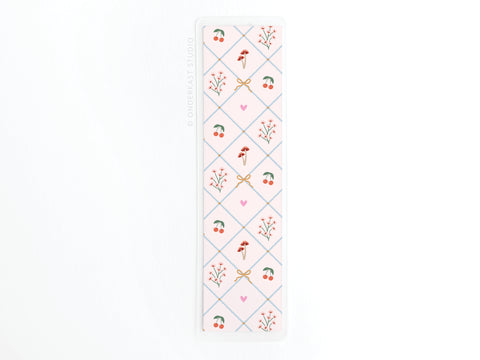 The Coquette Pattern Laminated Bookmark by Easyhand Goods features a pastel diamond design with cherries, flowers, mushrooms, and pink hearts on white. Printed in the USA.