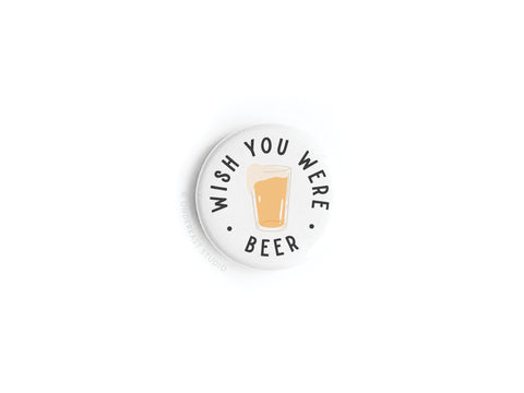 The Wish You Were Beer Button Magnet by Onderkast Studio is a round white magnet with a beer glass illustration and WISH YOU WERE BEER in black capitals—an ideal nostalgia gift for beer lovers.