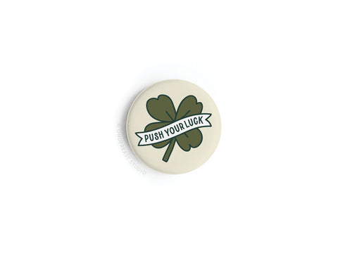 The Push Your Luck Clover Button Magnet by Onderkast Studio showcases a green four-leaf clover with PUSH YOUR LUCK on a white background—an ideal touch of Irish charm for your décor.