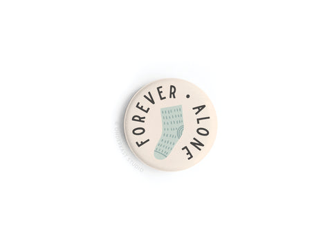 Show off your love for Onderkast Studio’s Forever Alone Sock Button Magnet—a round, playful pin with a single blue sock and FOREVER ALONE curved on a white background. A fun magnet for fans of this quirky design!.