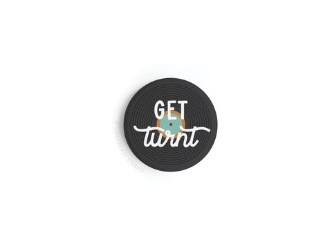 The Get Turnt Vinyl Button Magnet by Onderkast Studio is a round black magnet with record-like grooves, perfect for music lovers, featuring GET turnt in white cursive over a small globe illustration.