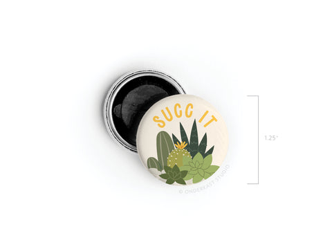 The Succ It Succulents Button Magnet by Onderkast Studio is a 1.25-inch round magnet with illustrated succulents and SUCC IT in yellow—ideal for plant lovers. The button’s partially open back reveals a black interior.