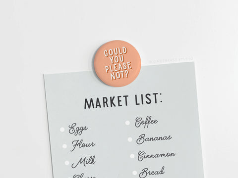 A grocery list held by the Onderkast Studio Could You Please Not Button Magnet – DISCONTINUED, featuring vibrant colors and made in the USA. List items: eggs, flour, milk, cheese, coffee, bananas, cinnamon, bread.
