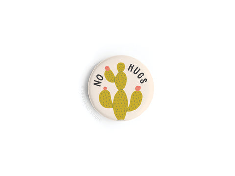 The No Hugs Cactus Button Magnet by Onderkast Studio features a green cactus with pink flowers and “NO HUGS” text on a white background—perfect as an introvert gift.