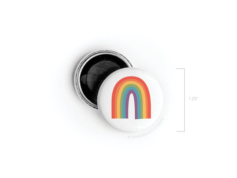 The Onderkast Studio Pride Rainbow Button Magnet features a simple six-arch rainbow flag on a white background. Shown with its open back, this round button magnet measures 1.25 inches in diameter.