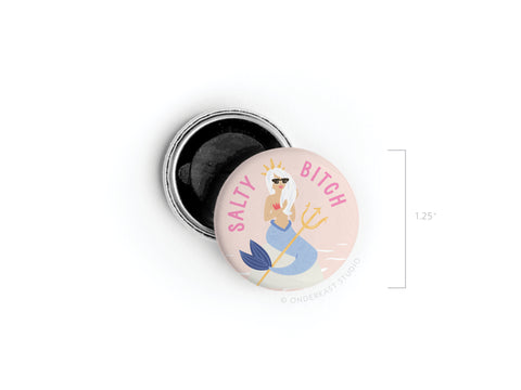 The Salty Bitch Mermaid Button Magnet by Onderkast Studio is a 1.25 round magnet featuring a crowned mermaid with a trident and sunglasses on a pink background—perfect for beach lovers and fun collections!.