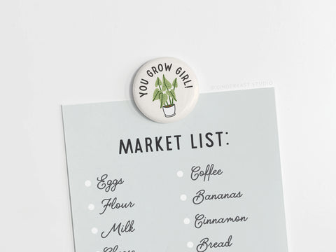The You Grow Girl! Houseplant Button Magnet by Onderkast Studio, featuring a plant illustration and motivational text, keeps your shopping list secure—ideal for plant lovers to remember eggs, flour, coffee, bananas, and more.