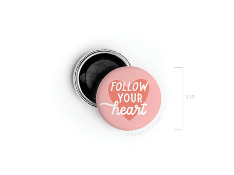 The Onderkast Studio Follow Your Heart Deep Button Magnet is a round, pink magnet with vibrant colors and white text, measuring 1.25 inches in diameter.
