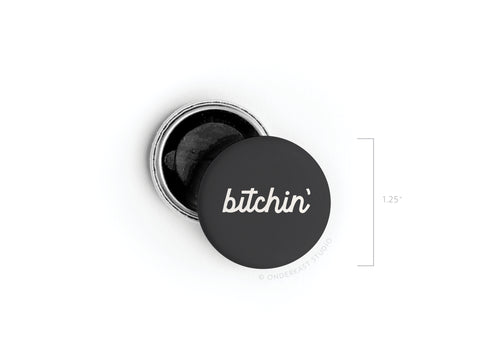 The Onderkast Studio Bitchin’ Button Magnet is a 1.25-inch round black magnet with “bitchin’” in white cursive on the lid, which is partially open to reveal a dark interior—perfect for adding retro coolness to any space.