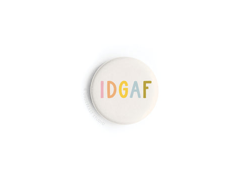 The IDGAF Button Magnet by Onderkast Studio is a round white magnet with pastel pink, orange, yellow, green, and blue lettering—an eye-catching accent that adds playful self-assurance and independence to any space.