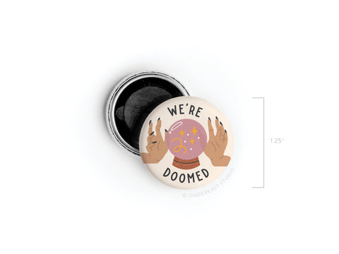 The We’re Doomed Button Magnet by Onderkast Studio features a crystal ball and hands with bold text in vibrant colors. Proudly printed in the USA, it measures 1.25 inches and is shown next to an open tin.