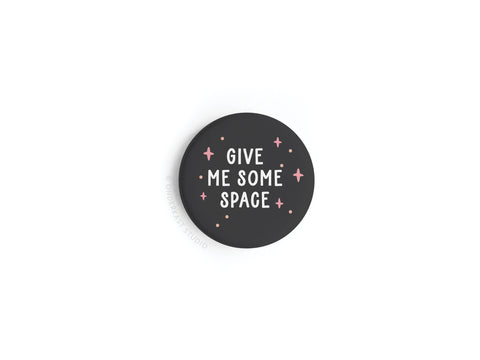 The Onderkast Studio Give Me Some Space Button Magnet is round, black, and features bold white text with small pink stars—a playful way to remind others to respect personal space.