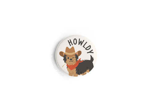 The Onderkast Studio Howldy Button Magnet features a cute dog in a cowboy hat and red bandana with HOWLDY above, all in vibrant colors on a crisp white background for a fun Western-inspired touch.