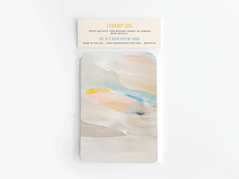 The Onderkast Studio Literary Log Book Review Card Set comes in clear packaging with a top label showing product details, and the front card displays an abstract pastel design in beige, yellow, blue, and peach on premium card stock.