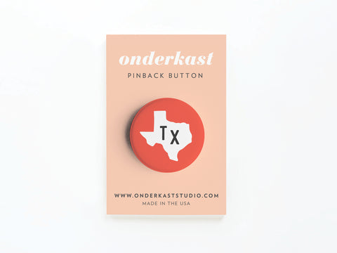 The Red TX Pinback Button by Onderkast Studio features a white Texas outline with black Tx letters on red, attached to a branded peach card—a stylish way to display your Texas pride.