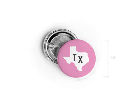 The Pink TX Pinback Button by Onderkast Studio features vibrant colors with a pink background, white Texas outline, and bold black TX letters. Measuring 1.25 wide, its the perfect accessory for displaying your Texas pride.