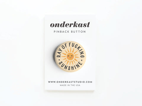 The Ray of Fucking Sunshine Pinback Button by Onderkast Studio features a playful sun illustration and comes on a branded card. Made in the USA, this humor pin makes a bold addition to any collection.