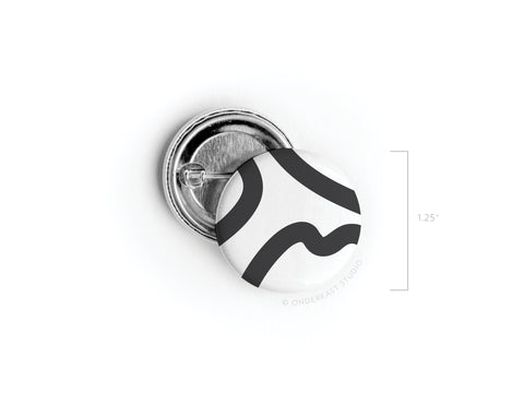 The Abstract No. 3 Pinback Button by Onderkast Studio features a crisp black squiggle on white, measures 1.25 across, and has a visible pin mechanism. Made in the USA. This item is discontinued.