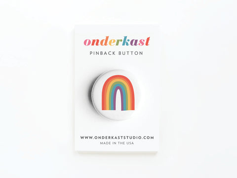 The Pride Rainbow Pinback Button by Onderkast Studio features a vibrant rainbow design on a card with colorful onderkast PINBACK BUTTON text, plus website and MADE IN THE USA—perfect for celebrating LGBTQ+ equality.