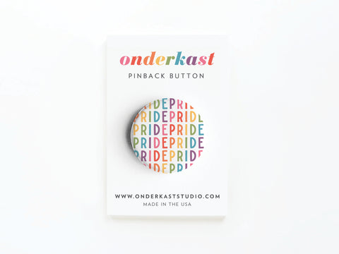 The Pride Pinback Button by Onderkast Studio features PRIDE in a rainbow gradient, symbolizing solidarity. It comes attached to a white Onderkast Studio card with website and MADE IN THE USA text at the bottom.