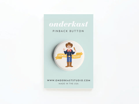 The Howdy Folks! Pinback Button by Onderkast Studio features a smiling cowboy with a banner, displayed on a light blue Onderkast card with website and “Made & printed in the USA” details.