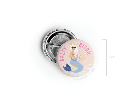The Salty Bitch Mermaid Pinback Button by Onderkast Studio features a sassy mermaid with a trident, sunglasses, and crown, plus “SALTY BITCH” in pink on a pastel background. Perfect for beach lovers. Measures 1.25 inches.