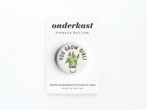 The You Grow Girl! Houseplant Pinback Button by Onderkast Studio features a potted plant and YOU GROW GIRL! text, attached to a card labeled Onderkast Pinback Button. Website and MADE IN THE USA are printed at the bottom.