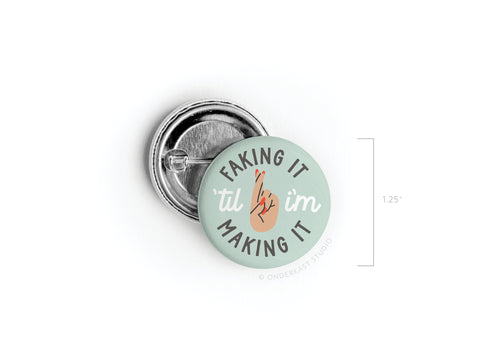 The 1.25 Faking It ’Til I’m Making It Pinback Button by Onderkast Studio features vibrant colors on light green. Til is replaced by a peace sign, symbolizing perseverance and determination.