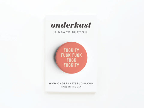 A vibrant Fuckity Fuck Fuck Fuck Fuckity Pinback Button by Onderkast Studio features cream adult humor lettering on a pink background, displayed on a white card labeled “onderkast pinback button.”.
