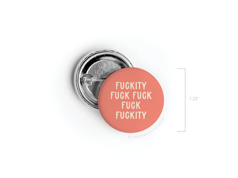 The Onderkast Studio Fuckity Fuck Fuck Fuck Fuckity Pinback Button is a round, pink 1.25-inch pin with bold white adult humor text. Its vibrant front design and back clasp are shown for detail.