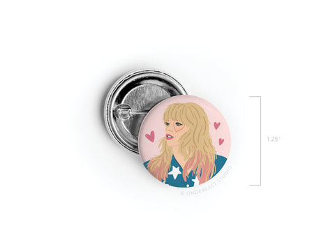 The TS Lover Pinback Button by Onderkast Studio is a 1.25-inch round button featuring an illustrated blonde woman in blue and white, surrounded by pink hearts—perfect for fans of enchanting lyrics and Taylor Swift.