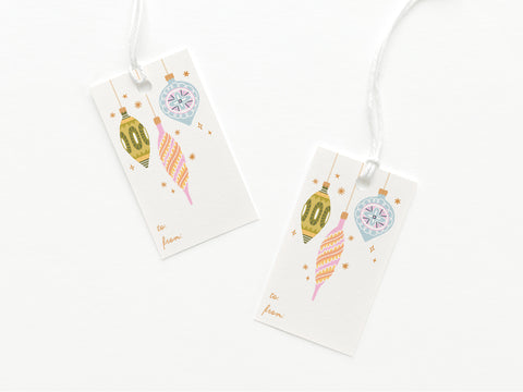 The Mod Ornaments Gift Tag by Onderkast Studio includes two smooth white card tags with vibrant green, pink, and blue ornament designs, gold to and from script, and attached white strings.