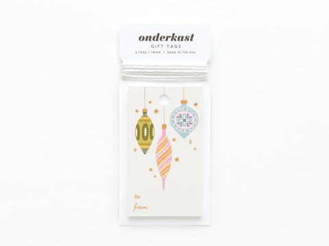 The Mod Ornaments Gift Tag by Onderkast Studio features vibrant illustrations of three hanging Christmas ornaments in green, pink, and blue on smooth white card stock. Each package reads onderkast GIFT TAGS and includes string for easy attachment.