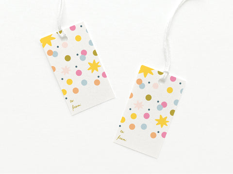 The Confetti Gift Tag by Onderkast Studio includes two sturdy US-made tags with white backgrounds, colorful polka dots and stars, plus “to:” and “from:” in lowercase cursive on the bottom left corner.