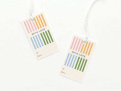 The Onderkast Studio With Love Cabana Stripes Gift Tag set includes two hand-assembled white card stock tags with pink, orange, blue, and green stripes, “WITH LOVE” centered, and “to” and “from” at the bottom. Strings are included.