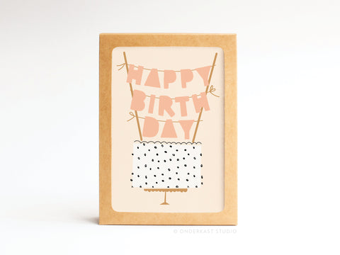 The Onderkast Studio Happy Birthday Cake Topper Folded Greeting Note Set of 10 features vibrant colors with pink birthday banners over a white cake with black sprinkles, all on a plain background and framed in a brown rectangular box.