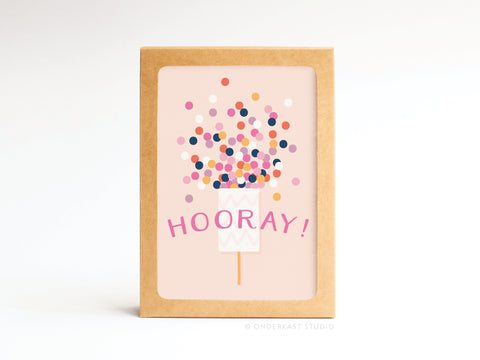 Celebrate with the Onderkast Studio Hooray! Confetti Popper Folded Greeting Note Set of 10, featuring HOORAY! in pink on a light pink card with party popper confetti and a brown border for a premium touch.