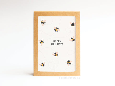 The Onderkast Studio Happy Bee-day! Folded Greeting Note Set of 10 features vibrantly printed cards with illustrated bees, “HAPPY BEE-DAY!” text in the center, and a brown border for a premium look. Cards are shown upright against a white background.