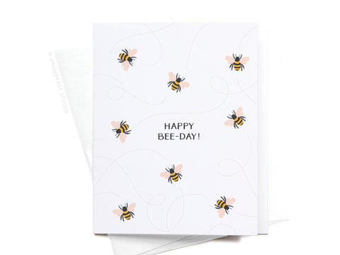 The Happy Bee-day! Greeting Card by Onderkast Studio features cute bee illustrations and swirly lines around the text on a white background, paired with a matching envelope for a premium touch.