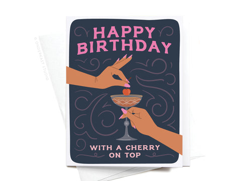 The Onderkast Studio Happy Birthday Cocktail With Cherry On Top Greeting Card features illustrated hands holding a Manhattan glass and placing a cherry on top, set against swirling patterns with the message Happy Birthday With a Cherry On Top.