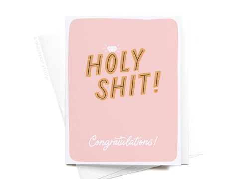 The Holy Shit Engagement Ring Greeting Card by Onderkast Studio features a pink background, bold gold “HOLY SHIT!” lettering, a diamond illustration, and “Congratulations!” in white script—perfect for engagements.