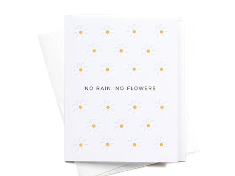 The No Rain, No Flowers Letterpress Greeting Card by Onderkast Studio features a grid of simple daisy illustrations and NO RAIN, NO FLOWERS in the center. An envelope is partially visible behind this charming encouragement card.