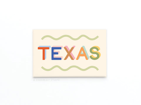 The Funky Texas Refrigerator Magnet by Onderkast Studio features bold, colorful TEXAS lettering framed by green wavy lines on a light cream background—a lively Lone Star State tribute for your fridge.