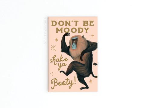 The Shake Ya Booty Baboon Refrigerator Magnet by Onderkast Studio features a dancing baboon and “DONT BE MOODY, shake ya Booty!” on a peach background with sparkles for a fun, uplifting vibe.